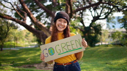 Go green Gen Z woman asia young people smile looking at camera showing save the earth planet world care banner poster sign in city nature tree public park. Protect future asian hope net zero waste.