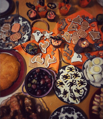 Delicious Halloween snacks shaped like mummies, eyes, and pumpkins, with pumpkin-shaped candles in the background, create a festive atmosphere.