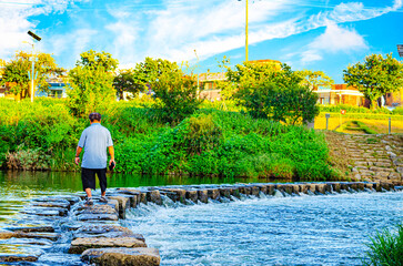 Obraz premium Man walking on stone bridge for across the river
