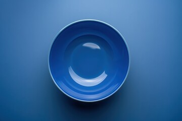 A blue ceramic bowl on a smooth blue surface