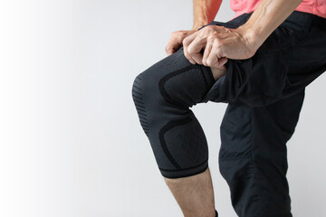 Man putting knee brace to  prevent and support  knee from painful problems. Health problems and pain.