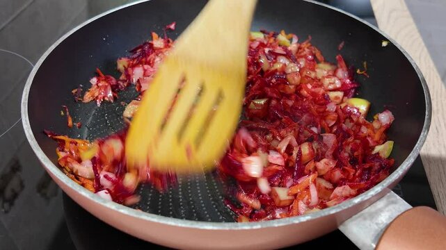 Woman's hands mixing roasted vegetables on frying pan