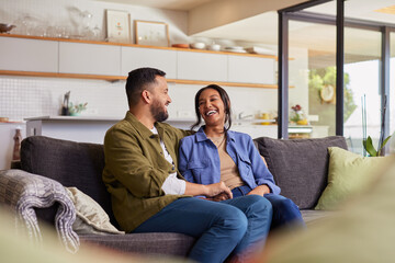 Mixed race couple laughing together at home in living room