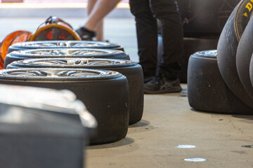 A line of prepared racing tires in a motorsport garage, a hand checking the tires - horizontal © Randal