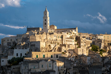 Obraz premium In the enchanting city of Matera, Puglia Italy, ancient stone buildings rise steeply against a vibrant sky, revealing a rich history.