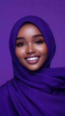 Naklejka premium An attractive young woman wearing a hijab, smiling against a solid purple background