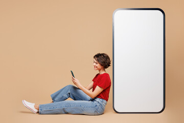 Full body side view young woman wear red t-shirt casual clothes sit near big huge blank screen...