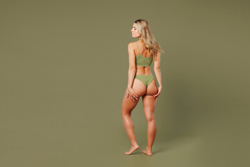 Full body back rear view young woman with slim skinny body perfect skin in top bra lingerie stand put hand on buttocks without cellulite isolated on plain green background Lifestyle diet fit concept