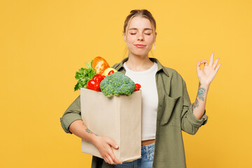 Young spiritual woman wear casual clothes hold bag for takeaway mock up food products hold hands in...