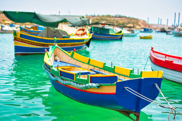 Traditional fishing boats in the Mediterranean Village of Marsaxlokk, Malta. July 2021 on a hot, sunny, summers day during the Covid 19 Pandemic. famous for its colourful fishing boats called Iuzzu.