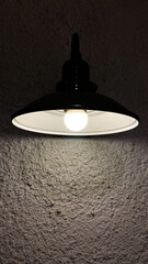 Black hanging lamp with white light against white wall. Close-up of black lamps on ceiling. Modern interior.