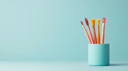 Collection of colorful art brushes in a blue holder on a light blue background. Creative tools concept.
