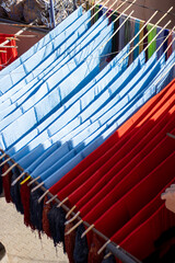 red and blue cloth hanging to dry hand dyed fabric material in a souk market in Marrakesh, Morocco