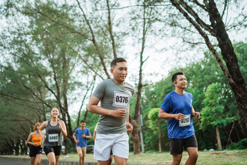 Fototapeta premium sporty man running through marathon track with other athlete