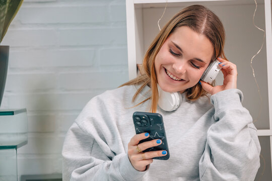 blonde girl at home with mobile phone and headphones