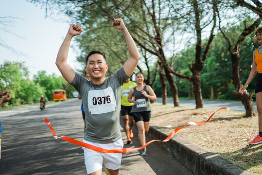 marathon runner crossing finish line with hands up gesture