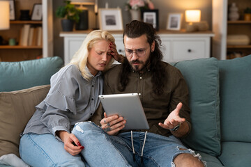 Woman comforts her husband who was confirmed via received email on tablet that he got fired at work and that he is no longer employed in the company where he expected to be promoted. Job lost concept