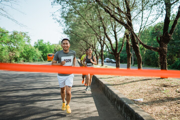 Obraz premium asian male marathon participant running towards finish line