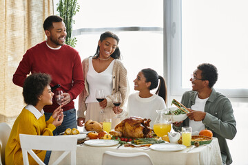 A group of friends enjoy a festive Thanksgiving meal, sharing stories and toasting together.