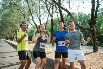 Obraz premium asian sporty people standing with fist pump gesture celebrating victory