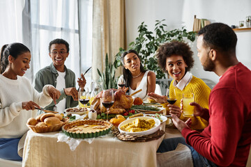 A cheerful group of friends enjoys a Thanksgiving feast together, sharing stories and food.