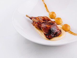 Roasted chicken legs with mashed potatoes and crispy balls on white plate