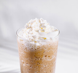 Iced coffee topped with whipped cream in a tall glass