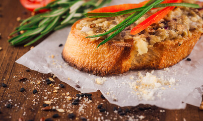 Delicious bruschetta with eggplant spread and fresh herbs sitting on wooden table