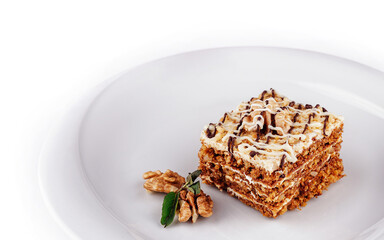 Delicious cake with walnuts and white chocolate drizzle sitting on white plate