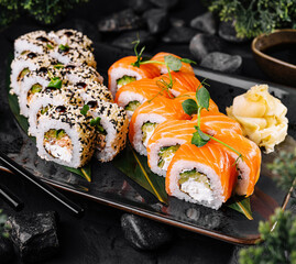 Sushi rolls set with philadelphia cheese, salmon, sesame and wasabi on dark background