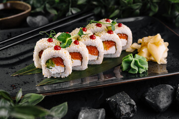 Sushi rolls covered with sesame seeds and red caviar lying on a plate