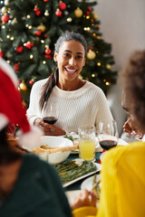 Friends gather at a festive table, sharing laughter and tasty food for Christmas.