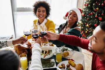 A joyful gathering of friends toasting glasses while enjoying a festive Christmas meal.