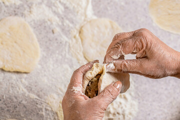 Grandmother baker hands making pie from dough. Homemade cooking. Process of making pies, hand. Hands pie dough. Dough for baking, pieces dough. Womans hands rolling doughs for pies © Yevhen