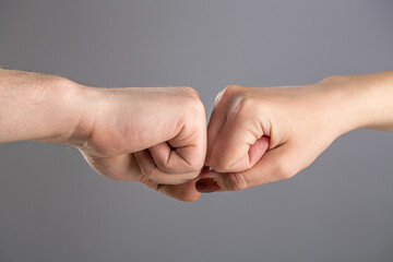 Man and a woman touching their fists. Fist Bump. Gesture of giving respect or approval. Friends greeting. Man and woman are fist bumping. Two male fists hitting each other. Teamwork and friendship.