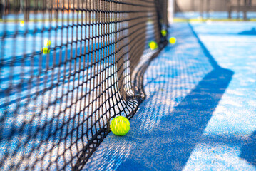Blue court with tennis net and yellow tennis ball. Preparing for game. Popular active new game padel. Side view.