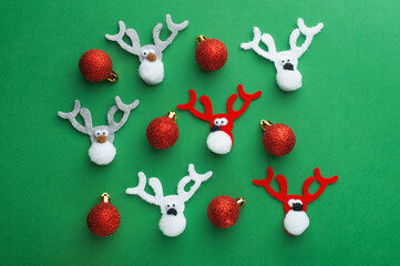 New Year background made of felt deer and red Christmas balls on a green background.
