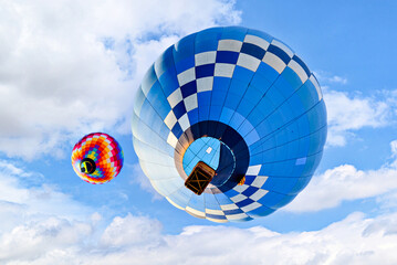 Blue hot air balloon flying on the blue sky with white clouds	