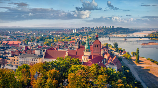 Aerial summer cityscape of Grudziadz town on east shore of river Vistula, Poland. Picturesque morning view of tower of Church of St. Nicholas the Bishop and Bronislaw Malinowski Bridge on background.
