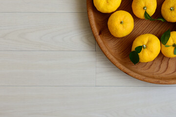 俯瞰で見た、白い背景に木の盆に乗ったたくさんの柚子の実