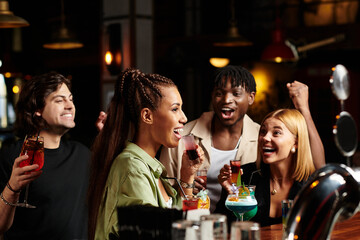 Colleagues celebrate together, raising colorful drinks and sharing laughter at a corporate event.