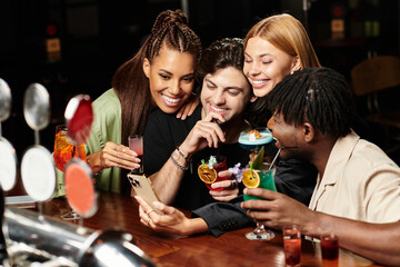 Young colleagues share laughter and drinks while capturing a fun moment at a festive gathering.