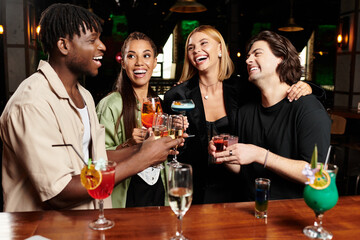 Colleagues celebrate with laughter and colorful cocktails at an evening gathering.