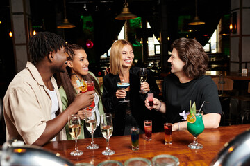 Young colleagues cheerfully toast with colorful drinks at a lively corporate event.