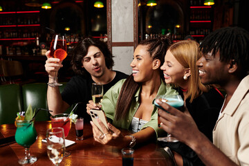 Colleagues enjoy a lively evening together, sharing drinks and laughter at a corporate gathering.