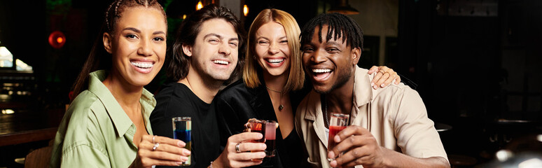 Diverse coworkers enjoy a fun evening together, raising their glasses in celebration at an event.