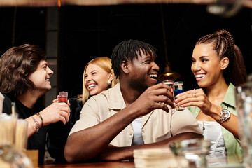 Young professionals enjoy each others company, sharing laughs and drinks during a vibrant party.