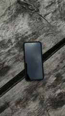 The phone lying on the old gray boards with the screen turned off