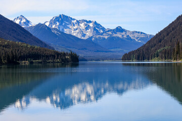 mountains are reflected in the smooth surface of duffey lake, british columbia