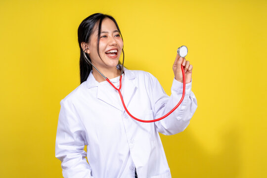 A woman in a white lab coat is holding a stethoscope and smiling